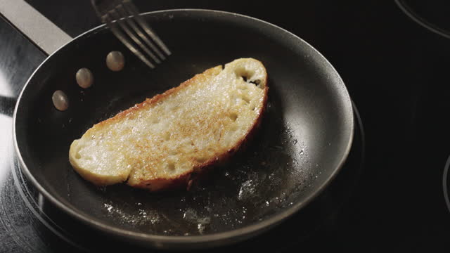 Turning Toasted Slice of SourDough Bread Over In a Pan with Butter, Toasting to a Golden Brown