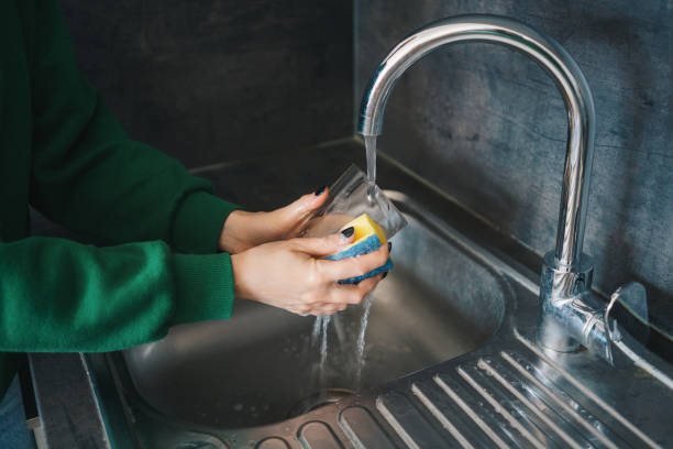 istock Woman washing a glass with a sponge in the kitchen 1998077155