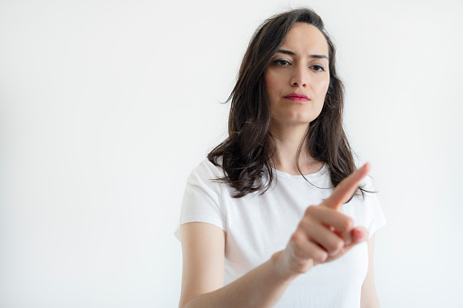 young woman pressing a virtual button with her index finger on white background