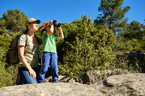 Happy mother and her young son birdwatching in natural park. Nature, exploration concept