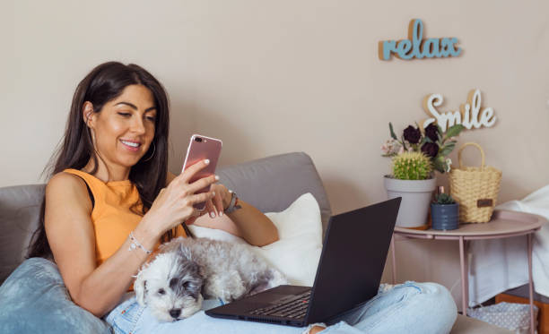 istock Smiling Woman using her phone at home 1998083248