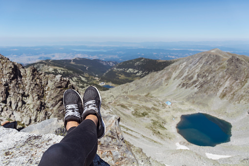 Personal perspective of woman  relaxing on top of Rila Mountain . Feet view . Travel vacations concept
