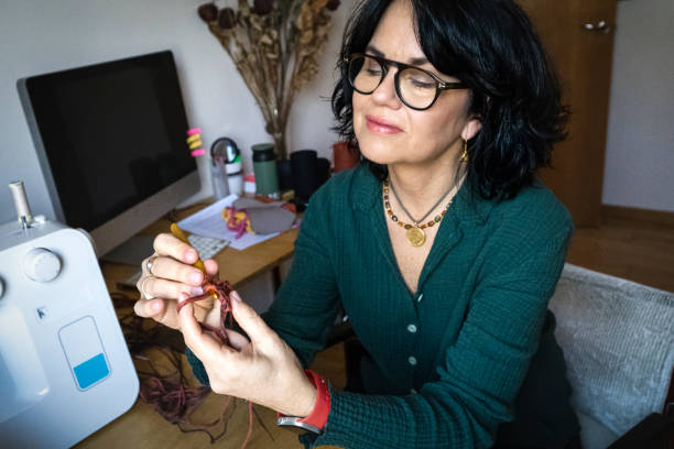 istock mature woman working from home, making crochet 1998094550