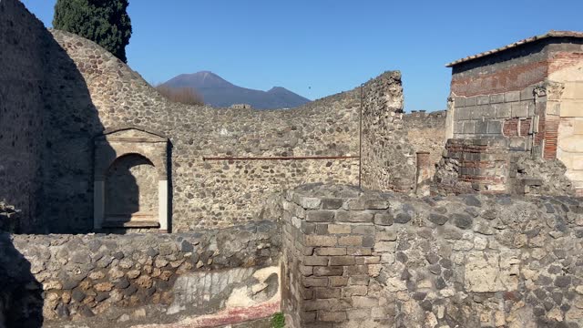 Old house in roman town of Pompeii with Vesuvius behind. Panning
