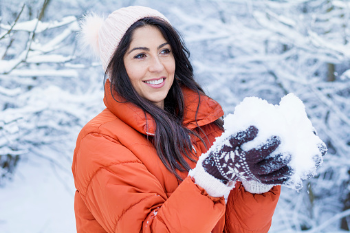 Portrait of happy young woman playing with snow in winter