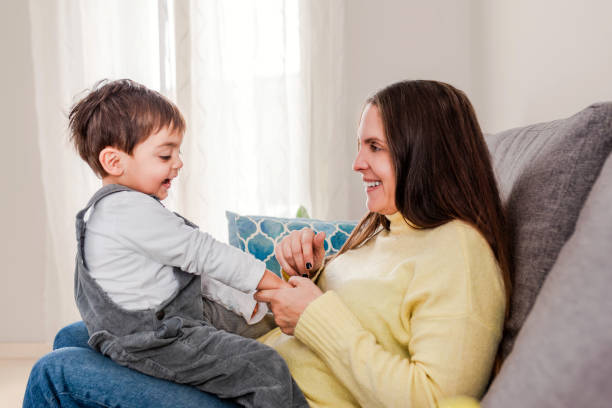 istock Joyful Mother Playing with Her Laughing Toddler Son on a Comfortable Sofa at Home 1998123534