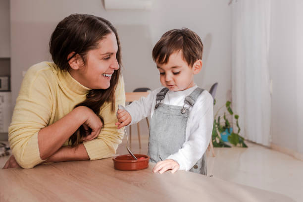 istock Loving Mother Watching Her Young Son Concentrating on Eating Breakfast on the Table 1998123557