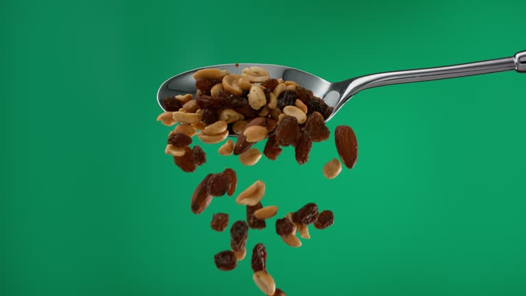 Super slow motion pile of nuts and dried fruit falling from a spoon