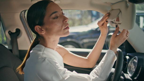 istock Brunette looking car mirror sitting front seat close up. Woman looking camera 1998134822