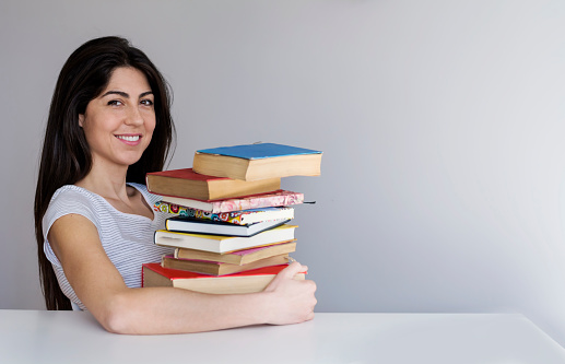 Portrait of young caucasian woman college student with many books