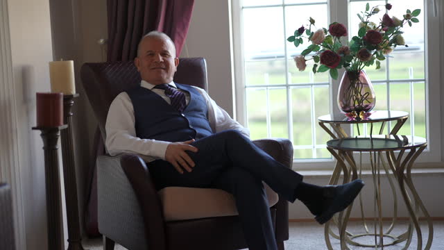 Mature man sitting on classic armchair in front of the window at home