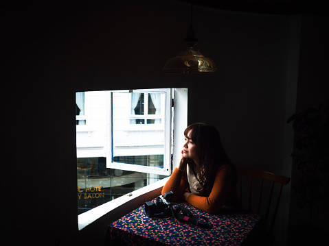 Relax Asian woman looking out the window alone. Pensive woman in front of the window. Portrait of a happy women commuting to looking out the window in the morning