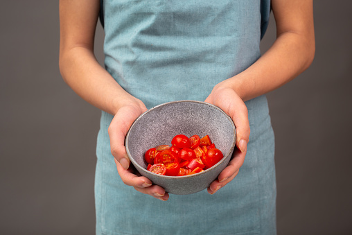 Tomato pieces in a bowl, prepare healthy food vegetables, holding fresh organic nutrition in the hands