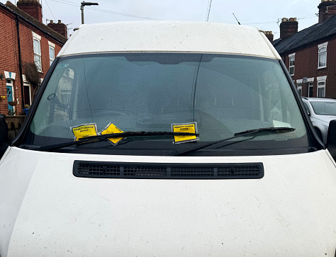 Parking tickets on a windscreen of a white van on an urban road