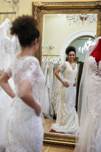 Young woman trying on a wedding dress in a bridal shop. About 25 years old, mixed-race brunette.