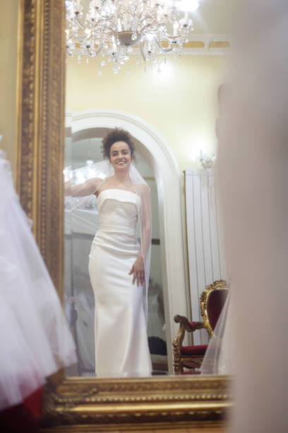 Young woman trying on a wedding dress in a bridal shop. About 25 years old, mixed-race brunette.