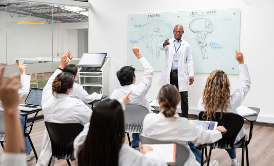 Group of medical students asking question to a teacher in class - medical school concepts