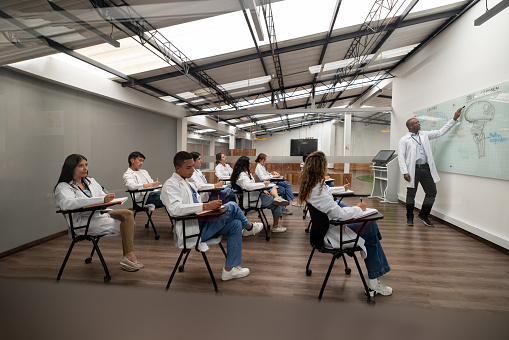 Group of Latin American medical students paying attention to the teacher in an anatomy class - medical school concepts