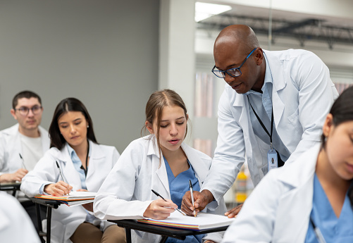 African American doctor teaching at a medical school and helping a student in class