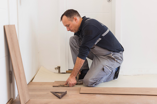 Man fixing hardwood floor at his home