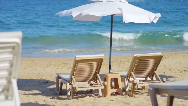 Beach chairs and umbrella with calm sea in the background in 4k slow motion 60fps