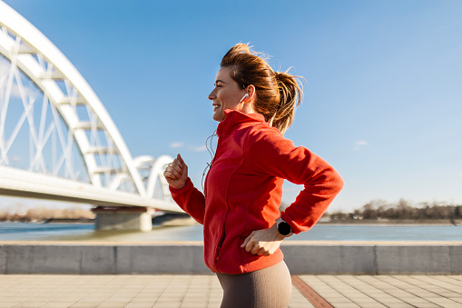 Happy sportswoman jogging at the bridge