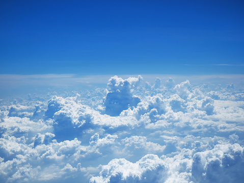 Aerial view on white fluffy clouds. flight over the clouds. view of the clouds from the airplane window. Nature view soft white clouds on pastel blue sky background.