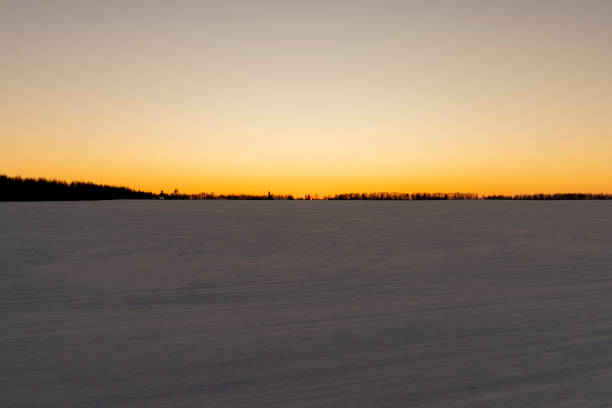 winter field covered with snow at sunset, beautiful multicolored sky at sunset in winter