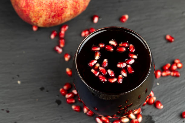 red ripe pomegranate and pomegranate juice on the table, tart pomegranate juice and red pomegranate close-up