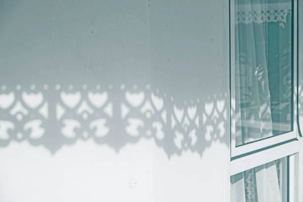 Sunlight shines through white wooden slats. Beautiful shadow on building wall. used for background and display your product.