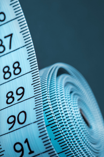 Close-up of a blue rolled up tape measure. Shallow depth of field, space for copy.