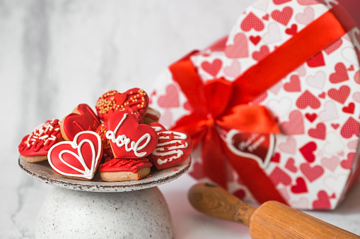 Homemade ginger cookies in the shape of a heart in red icing sugar. Delicious ginger cookies heart on a light concrete background. Freshly baked gingerbread cookies for Valentine's Day.