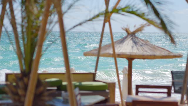 Tropical beach cabanas with thatched umbrellas in 4k slow motion 120fps