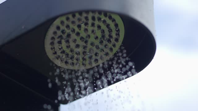Water flowing from a dark shower head in 4k slow motion 120fps