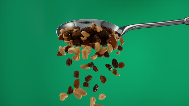 Super slow motion pile of nuts and raisins falling from a spoon