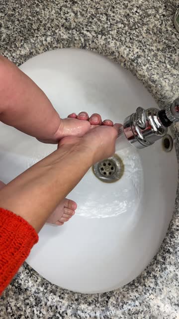 Little baby's feet being washed in the sink