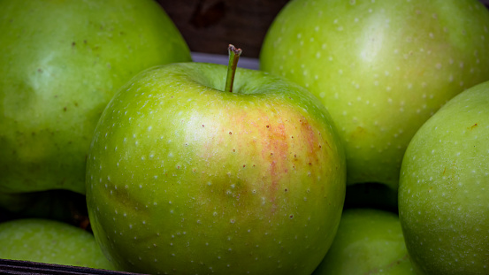 Ripe green apples in a wooden crate, close up isolated.