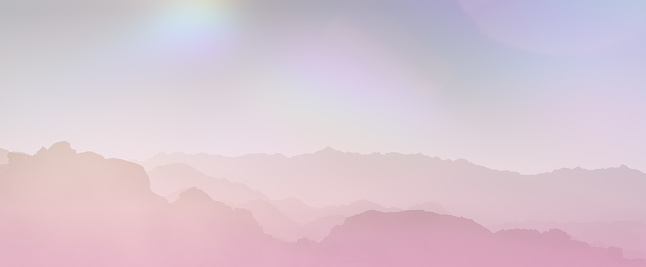 Gradient iridescent soft pink and purple hues wash over a layered mountain silhouette under a gentle dreamy sky. Abstract science fiction panoramic background. Futuristic fantasy landscape, sci-fi.