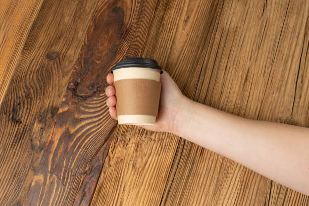 istock Hand Holds Cup, Empty Paper Cup in Hands, Coffee Mug, Teacup, Hot Beverage Mockup, Cup in Arms 1998435845