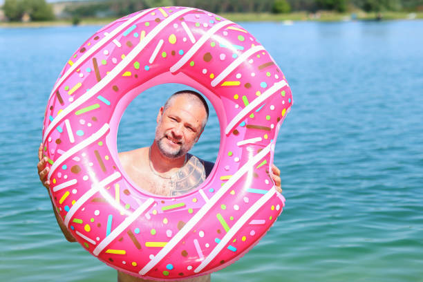 a middle-aged man looks through an inflatable ring at the sea