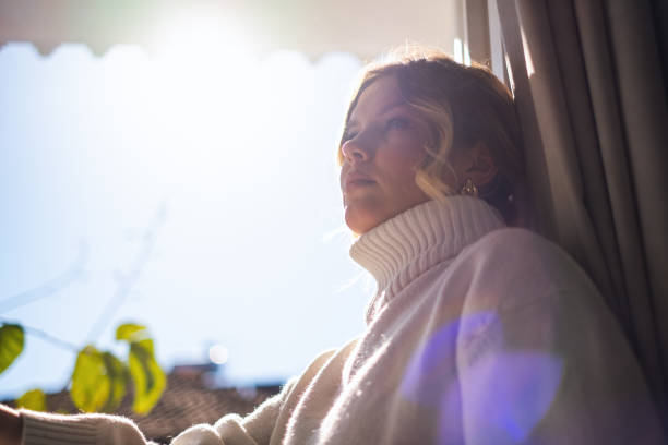 istock Young Woman Sitting and Looking Through Window 1998444290