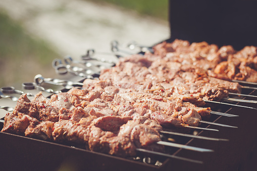 Close-up of beef shashlik skewers on a grill with evenly cooked meat and grill marks. Blurred background with a nice bokeh effect. Perfect for a summer barbecue or party.