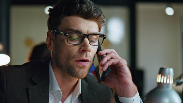 istock Stressed manager speaking mobile phone at office investment statistics closeup. 1998479881