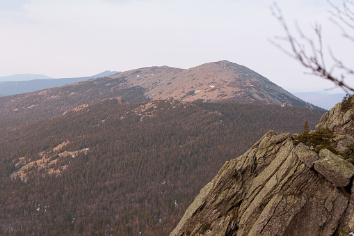 Rugged beauty of the rocky mountain range, a scene of solitude and peace with wind through trees, dramatic rock outcropping, and scraggly trees symbolizing resilience and hope in the wilderness.