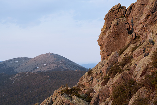 The rugged rock face of a mountain in the wilderness creates a striking profile against the sky. A great stock image for travel, adventure, or geology articles or websites.