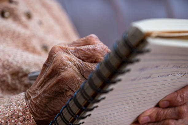 istock wrinkled hands for elderly person writing notes on his note book 1998490688