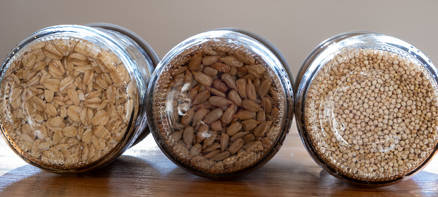 Grains and seeds in glass jars showing the texture of the seeds representing sustainable living, reduce, reuse, recycle and zero waste kitchens.