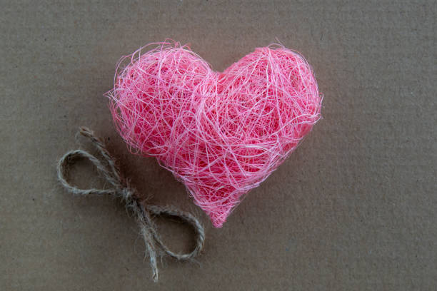 Heart shape made of pink material fabric on a rustic natural background with copyspace. Concept of Valentine's day and romantic love.