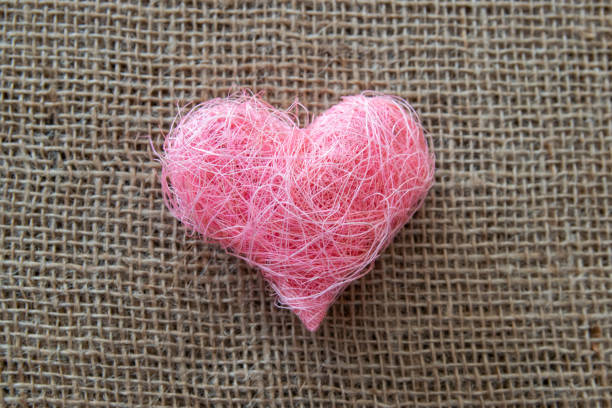 Heart shape made of pink material fabric on a rustic natural background with copyspace. Concept of Valentine's day and romantic love.