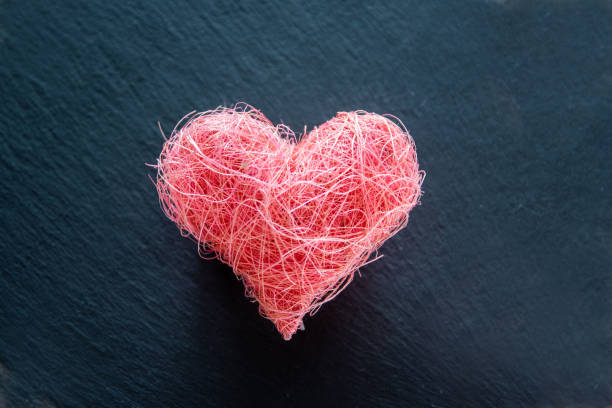 istock Pink fabric heart shape over black nature background. 1998562791